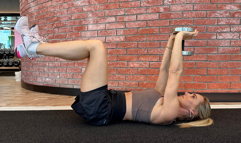 Lie on the ground holding a dumbbell over your chest with both arms straight