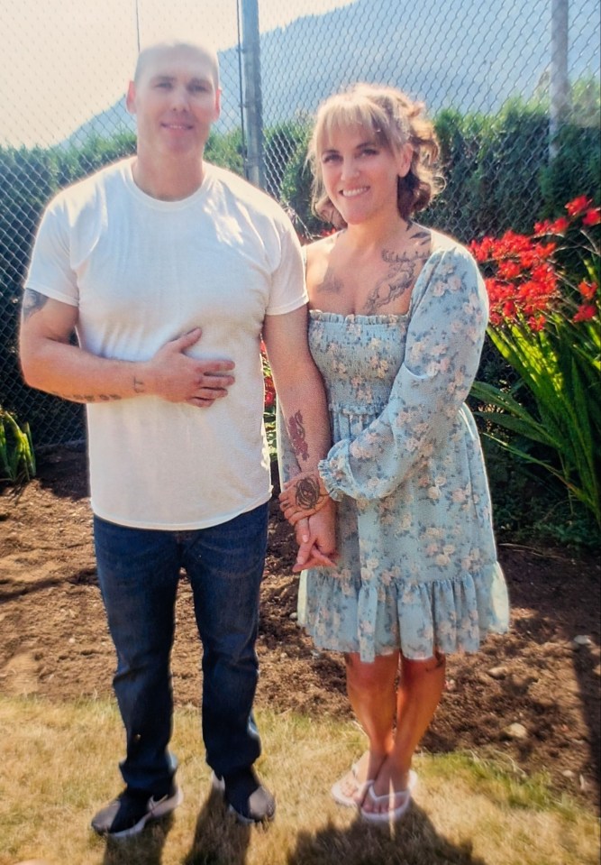 a man and a woman holding hands in front of a chain link fence