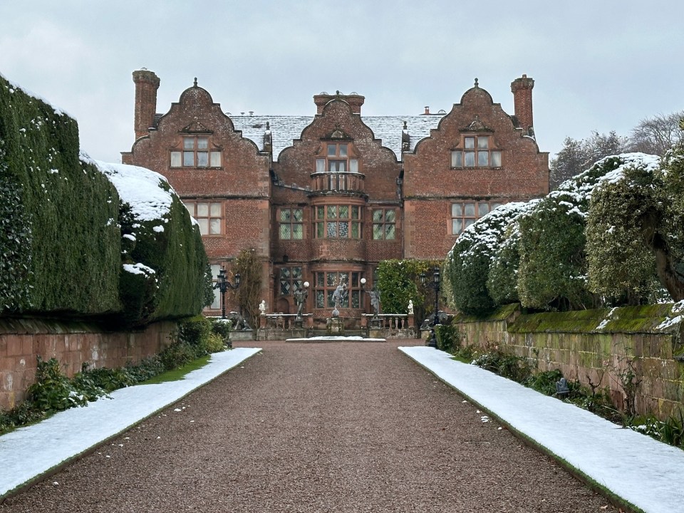 a snowy driveway leading to a large brick building