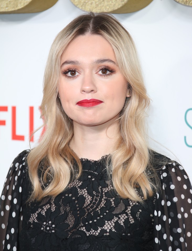 a woman in a black and white polka dot dress stands in front of a netflix logo