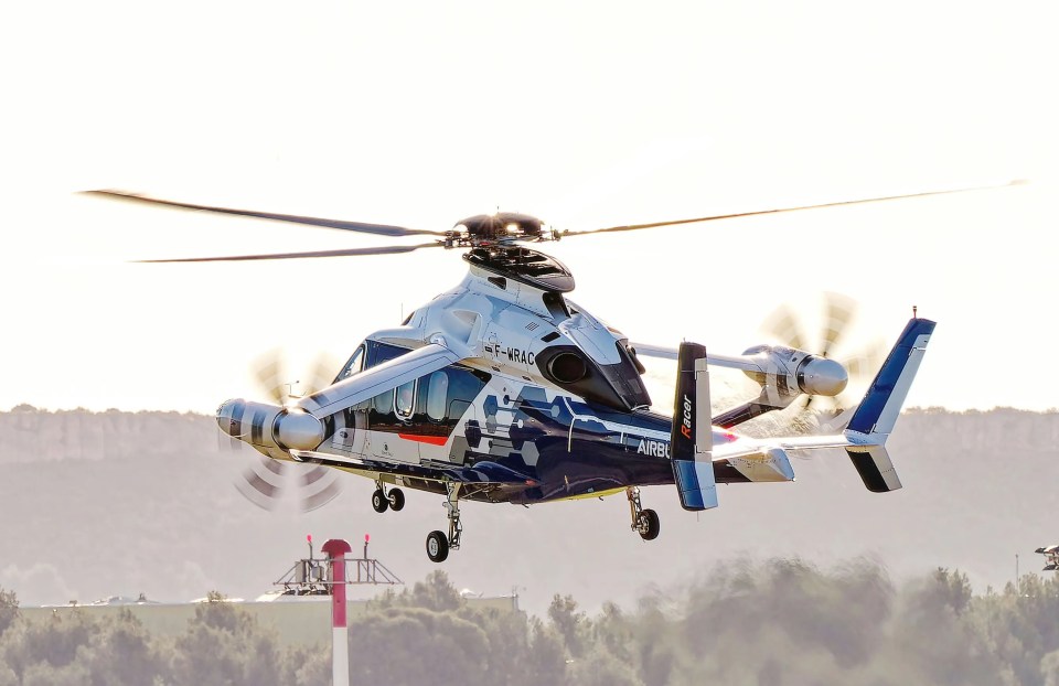 an airbus helicopter is flying over a field