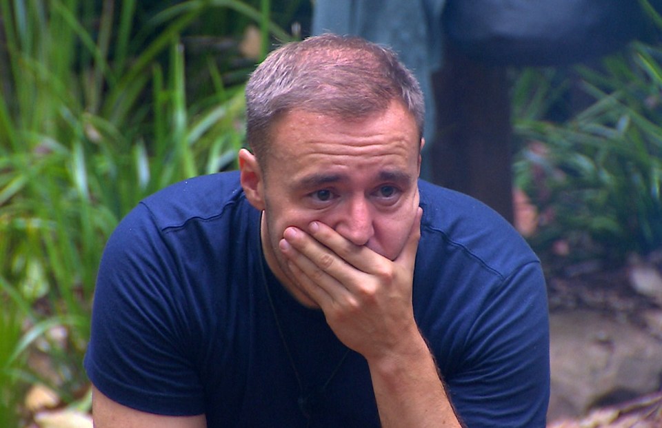 a man in a blue shirt is covering his mouth with his hand