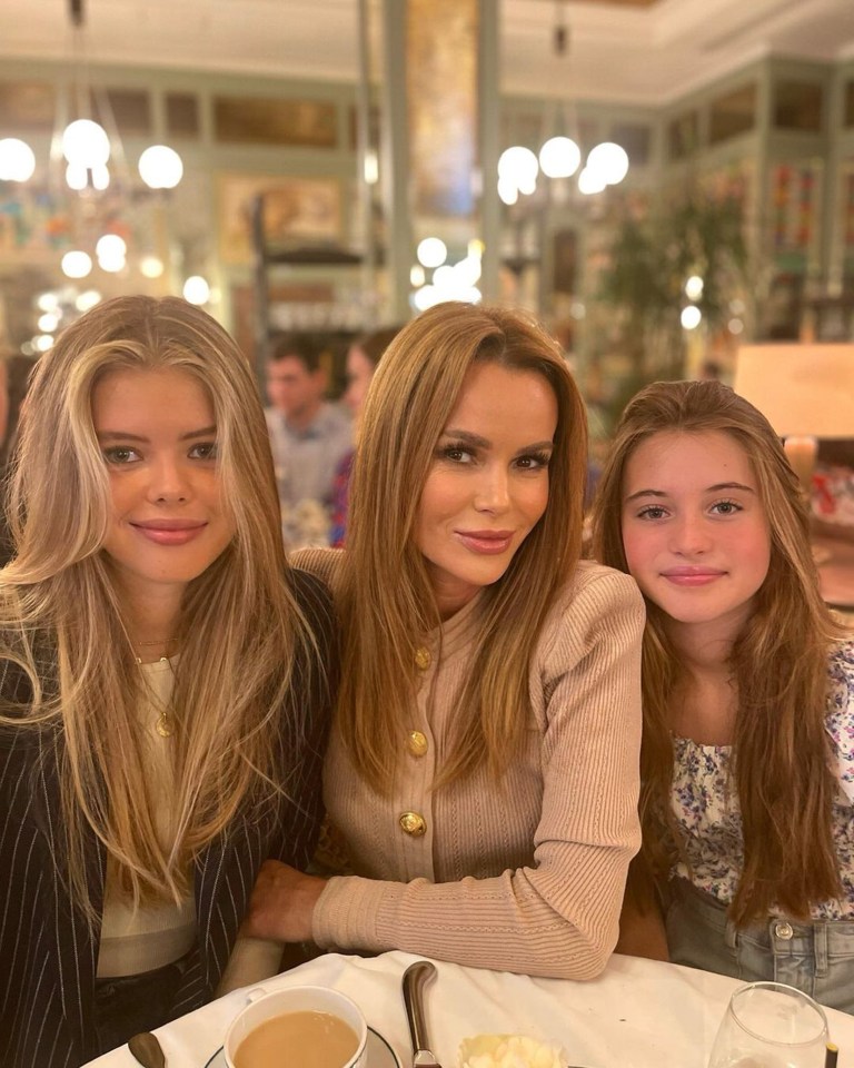 a woman and two girls sit at a table with a cup of coffee