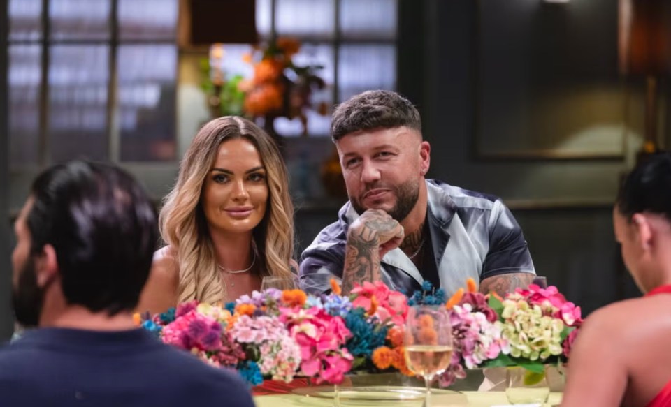 a group of people are sitting at a table with flowers and wine glasses