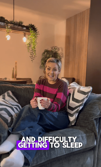 a woman is sitting on a couch holding a cup of coffee