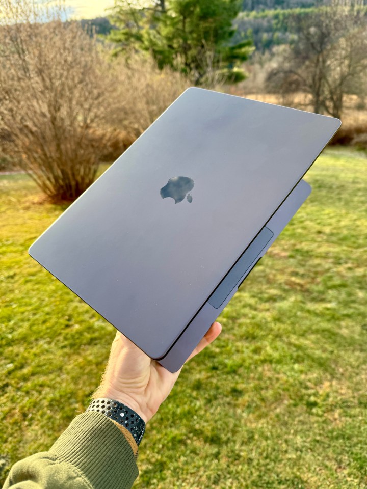 a person is holding an apple laptop in their hand