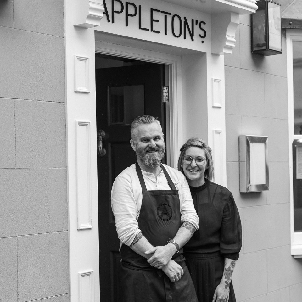 a man and a woman stand in front of appleton 's restaurant