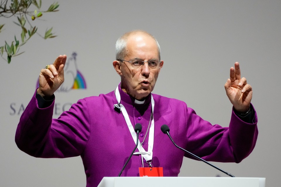 a man in a purple robe stands at a podium with his hands in the air