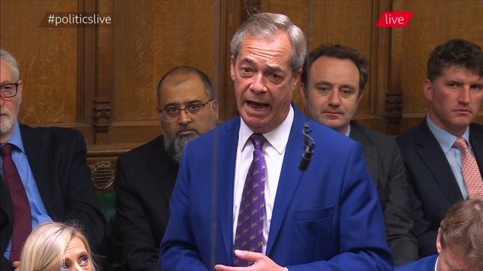 a man in a blue suit is giving a speech in front of a live audience