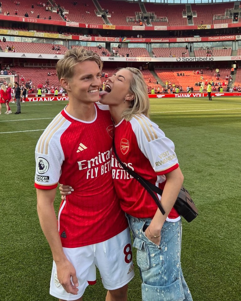 a man in a red emirates fly better jersey stands next to a woman