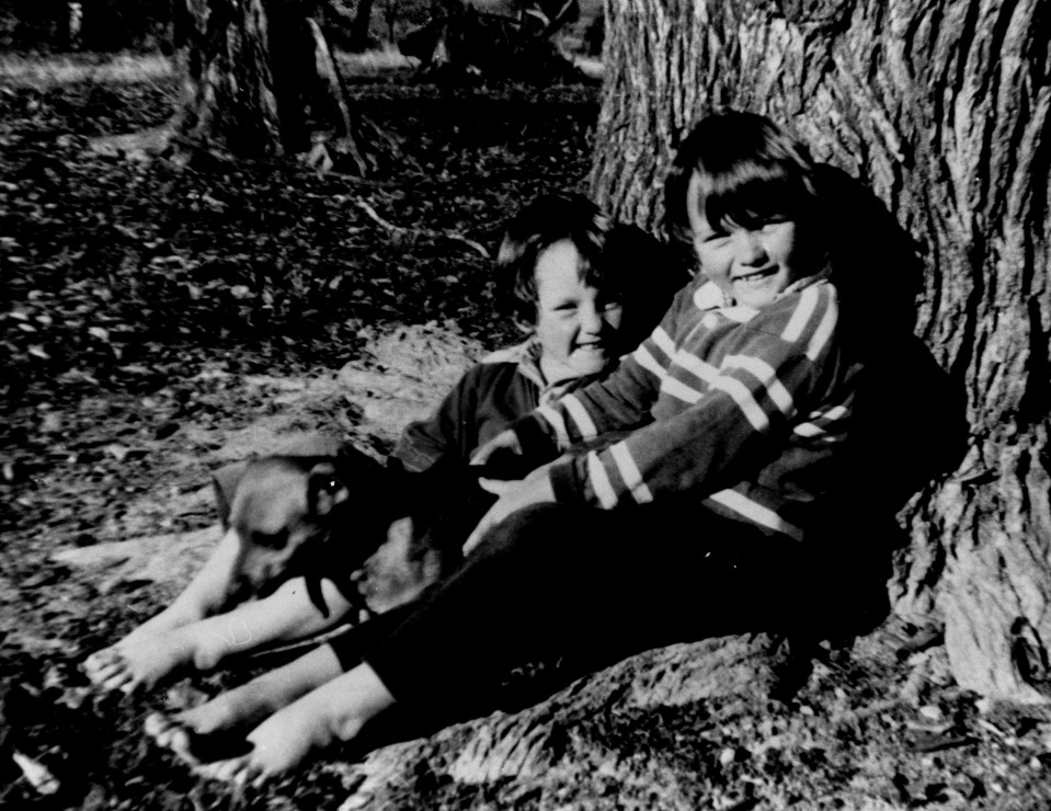 a black and white photo of two girls sitting under a tree