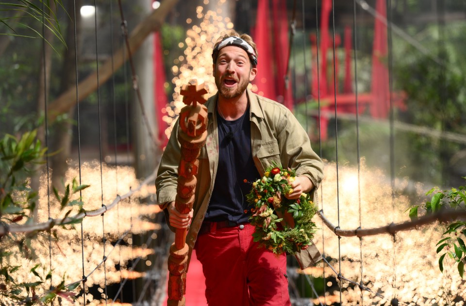 a man is holding a trophy and a wreath on a red carpet