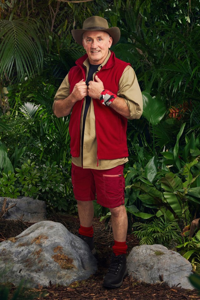 a man in a cowboy hat is standing in the jungle