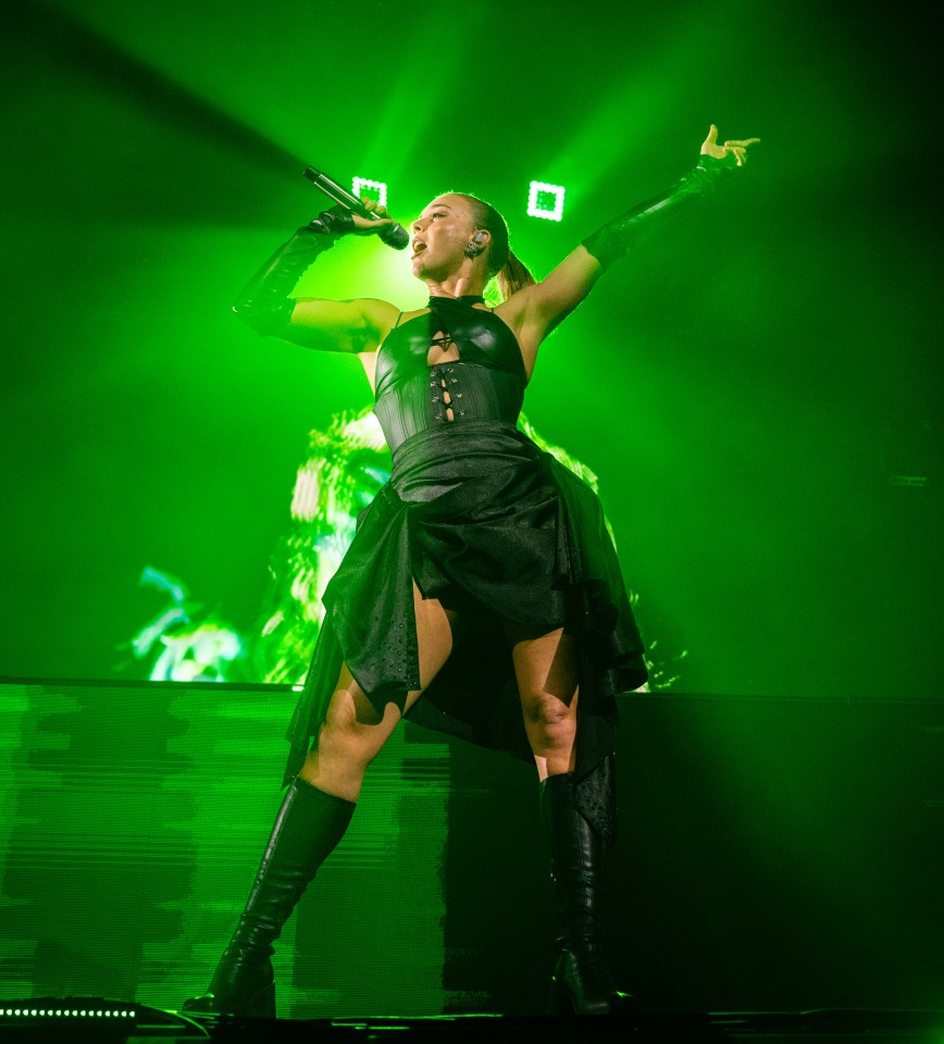 a woman in a black dress is singing into a microphone