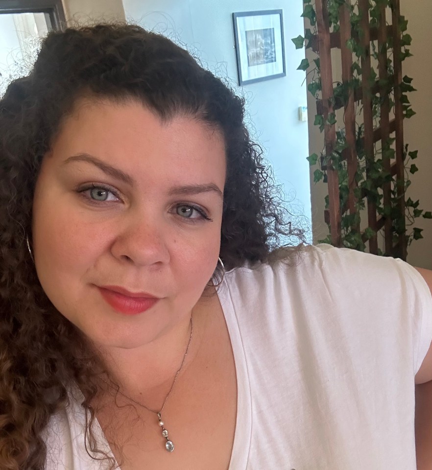 a woman with curly hair is wearing a white shirt and a necklace