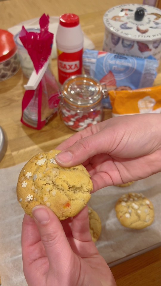 a person holding a cookie in front of a bag of baxa