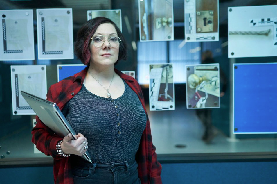 a woman is holding a laptop in front of a wall with papers on it that have the letter l on them