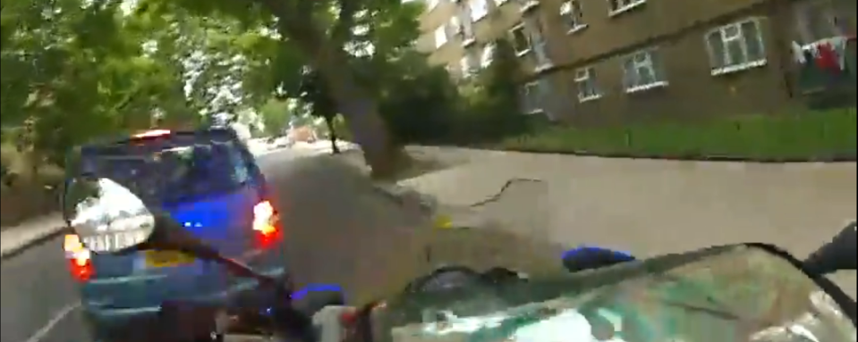 a motorcycle is driving down a street with a blue van behind it