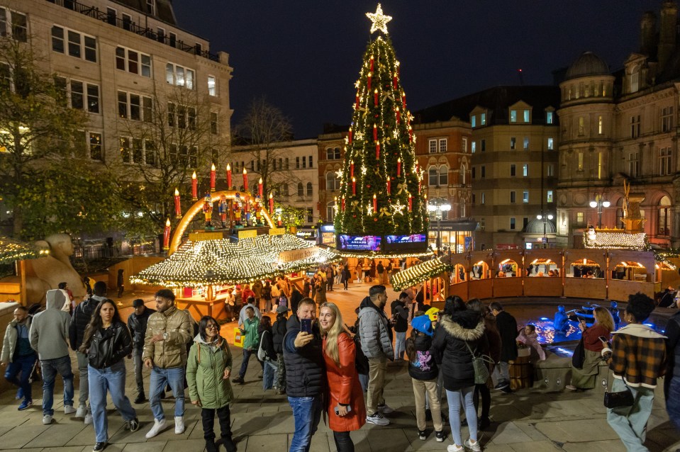 a crowd of people are gathered around a christmas tree with a star on top