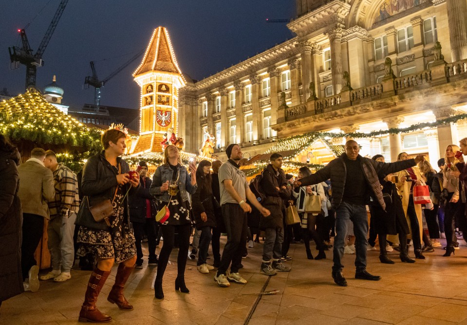 a group of people are dancing in front of a clock tower