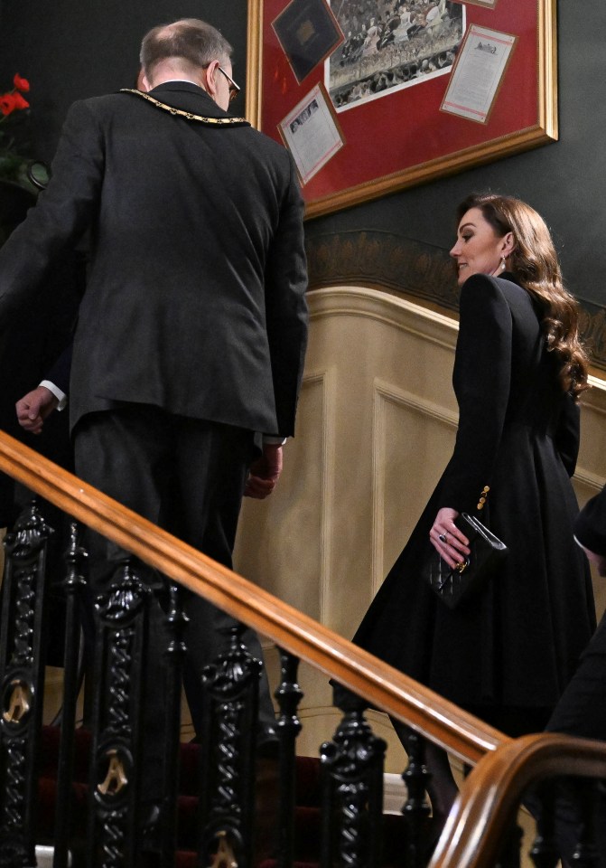 Kate makes her way up the stairs to take her seat holding a black Chanel clutch