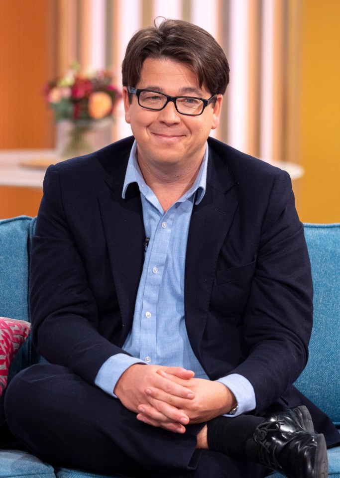 a man in a suit and glasses sits on a blue couch