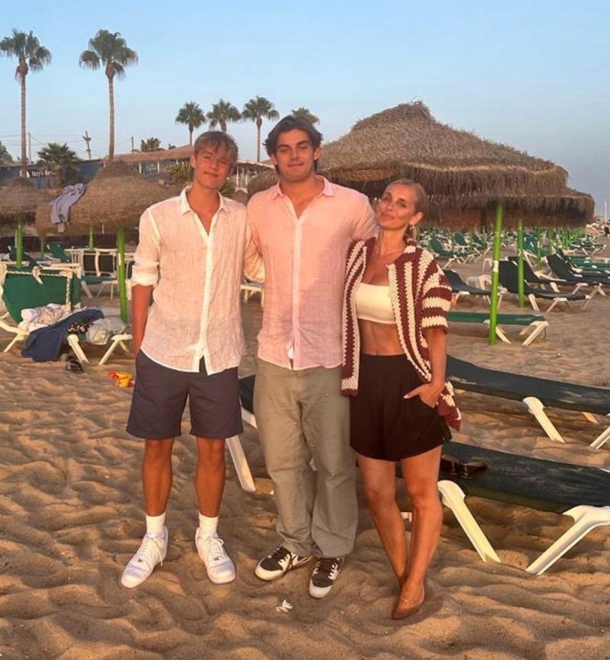 three people standing on a beach with palm trees in the background