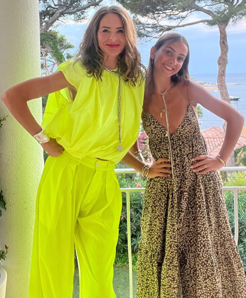 two women standing next to each other on a balcony with trees in the background