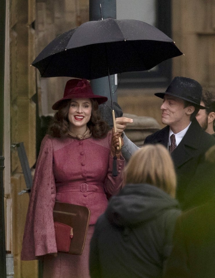 a woman in a red hat holds an umbrella over her head