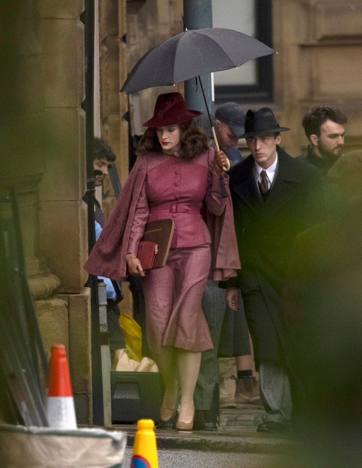 a woman in a pink suit is holding an umbrella