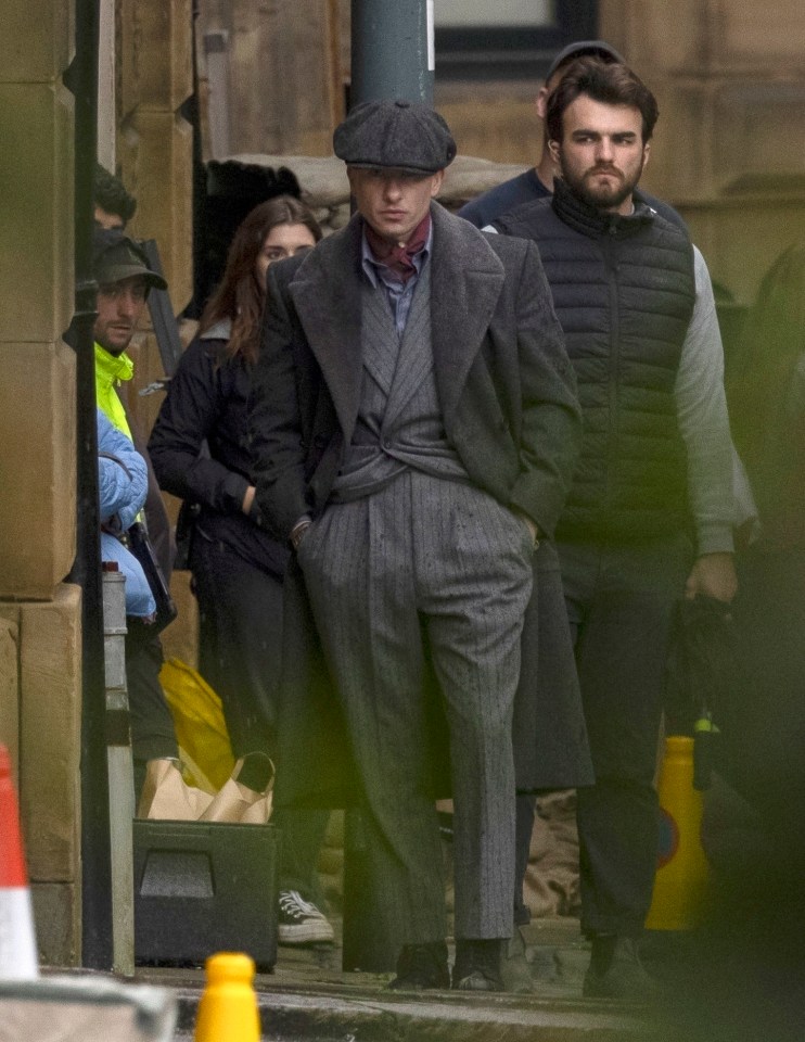 a man in a suit and hat is walking down a street