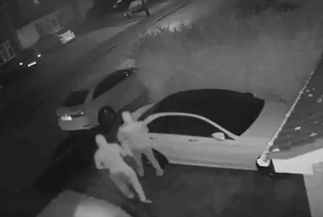 Two thieves approach a Mercedes parked on a driveway in the dead of night