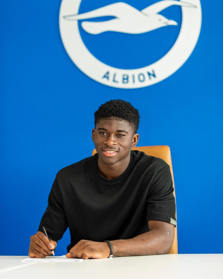 a man sits at a desk in front of a sign that says albion