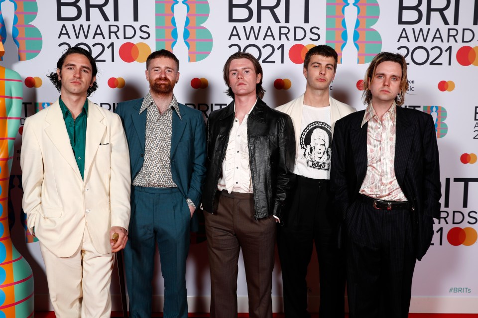 a group of men standing in front of a wall that says brit awards 2021