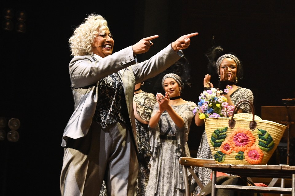 a woman pointing at a basket of flowers on a table