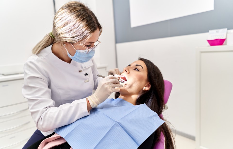 a woman is getting her teeth examined by a female dentist