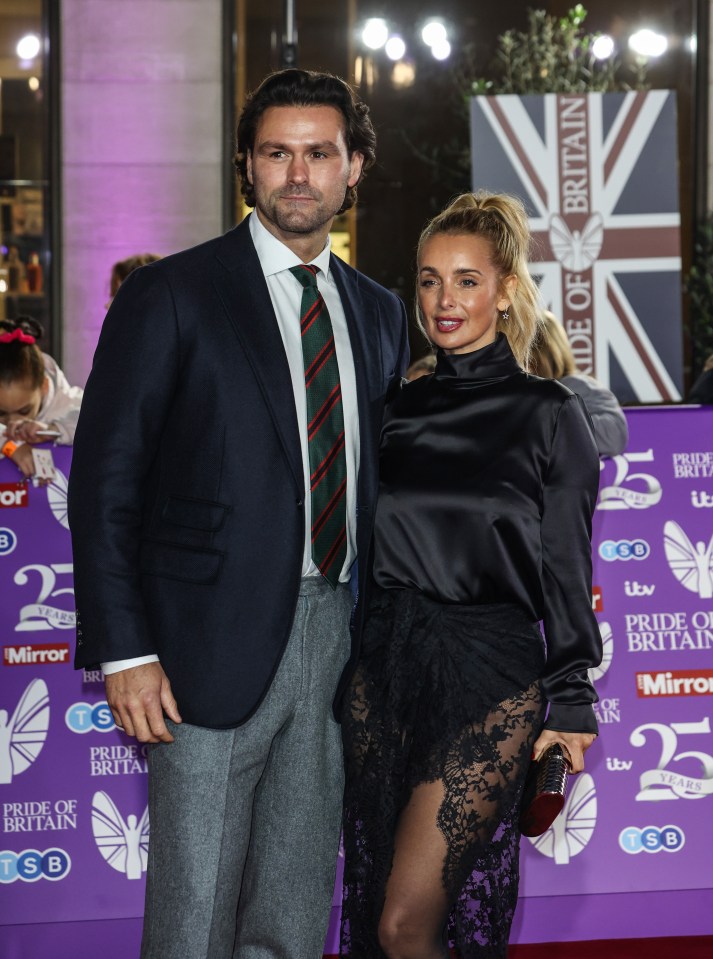 a man and woman pose on a red carpet in front of a sign that says pride of britain