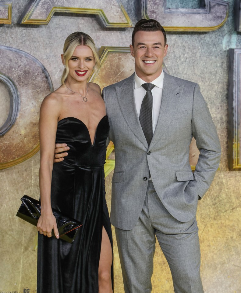 a man in a suit and tie stands next to a woman in a black dress