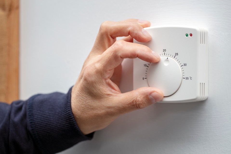 a person is adjusting a thermostat to 35 degrees celsius