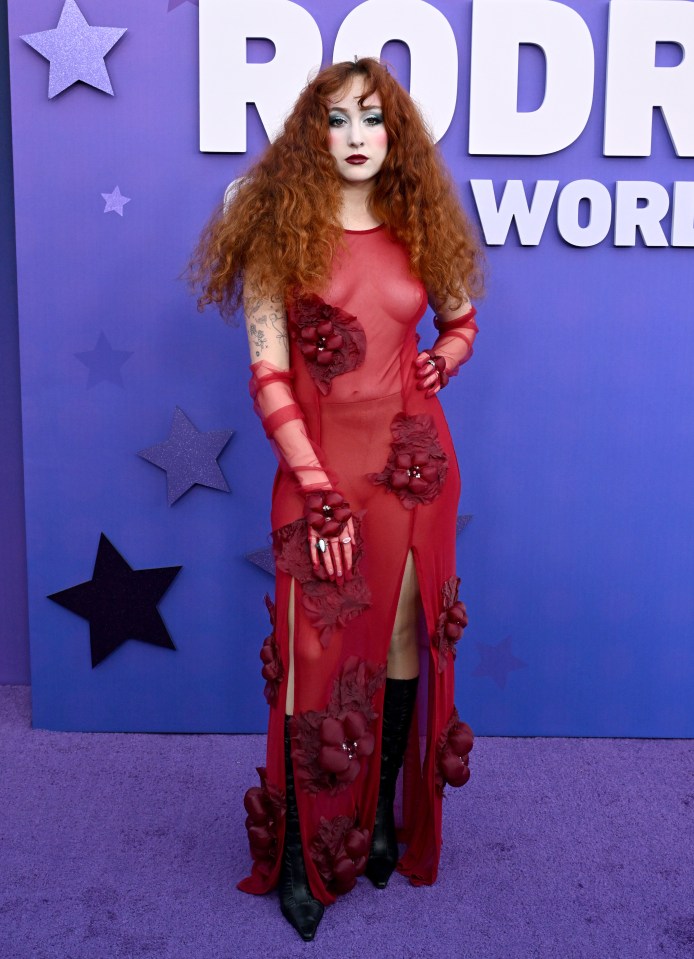 a woman in a red dress stands in front of a sign that says rodr world