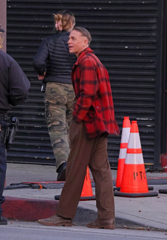 a man in a plaid shirt stands in front of a ptc traffic cone