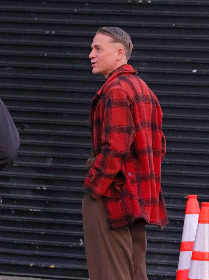 a man wearing a red plaid jacket and brown pants