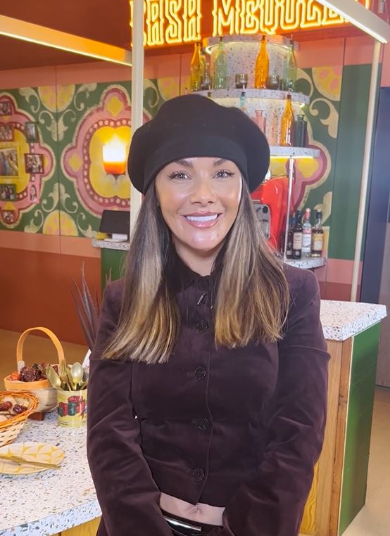 a woman wearing a black beret is smiling in front of a sign that says rsh