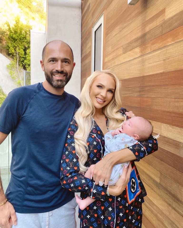 a man and woman holding a baby in front of a wooden wall