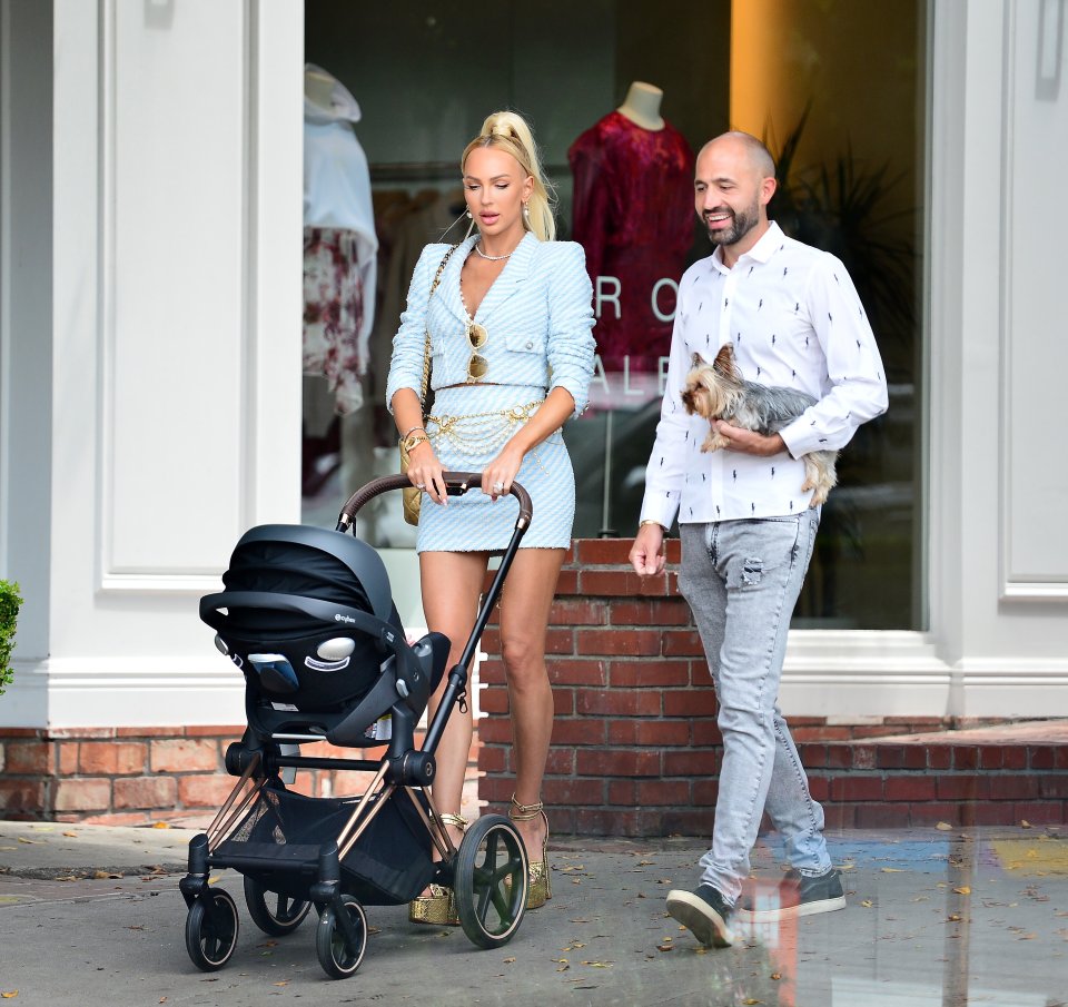 a woman pushing a stroller next to a man holding a dog