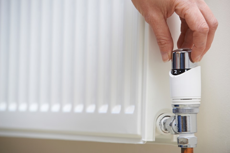 a person is adjusting the thermostat on a radiator to the number 2