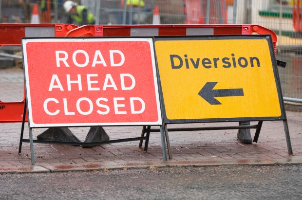 a red sign that says road ahead closed next to a yellow sign that says diversion