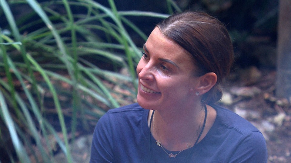 a woman wearing a blue shirt and a necklace with the letter t on it