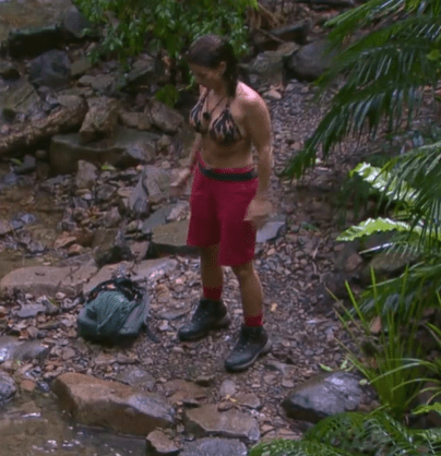 a woman in a bikini is standing next to a river