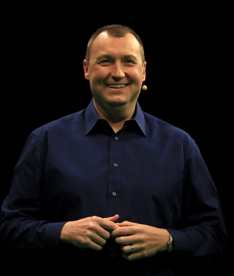 a man in a blue shirt is smiling in front of a microphone